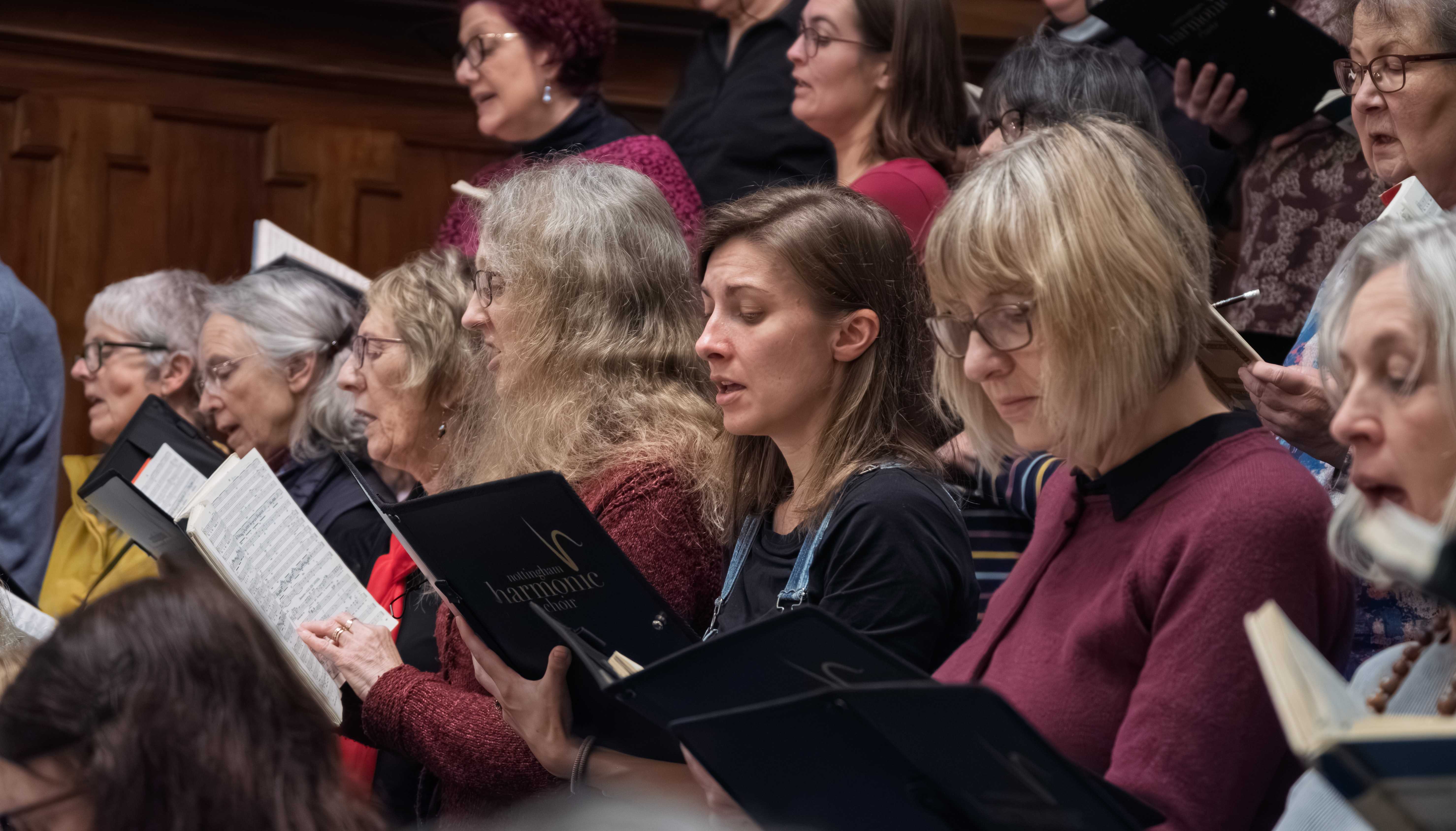 Part of the choir at a dress rehearsal in the Albert Hall, Nottingham.   The singers are dressed informally and are holding musical scores.