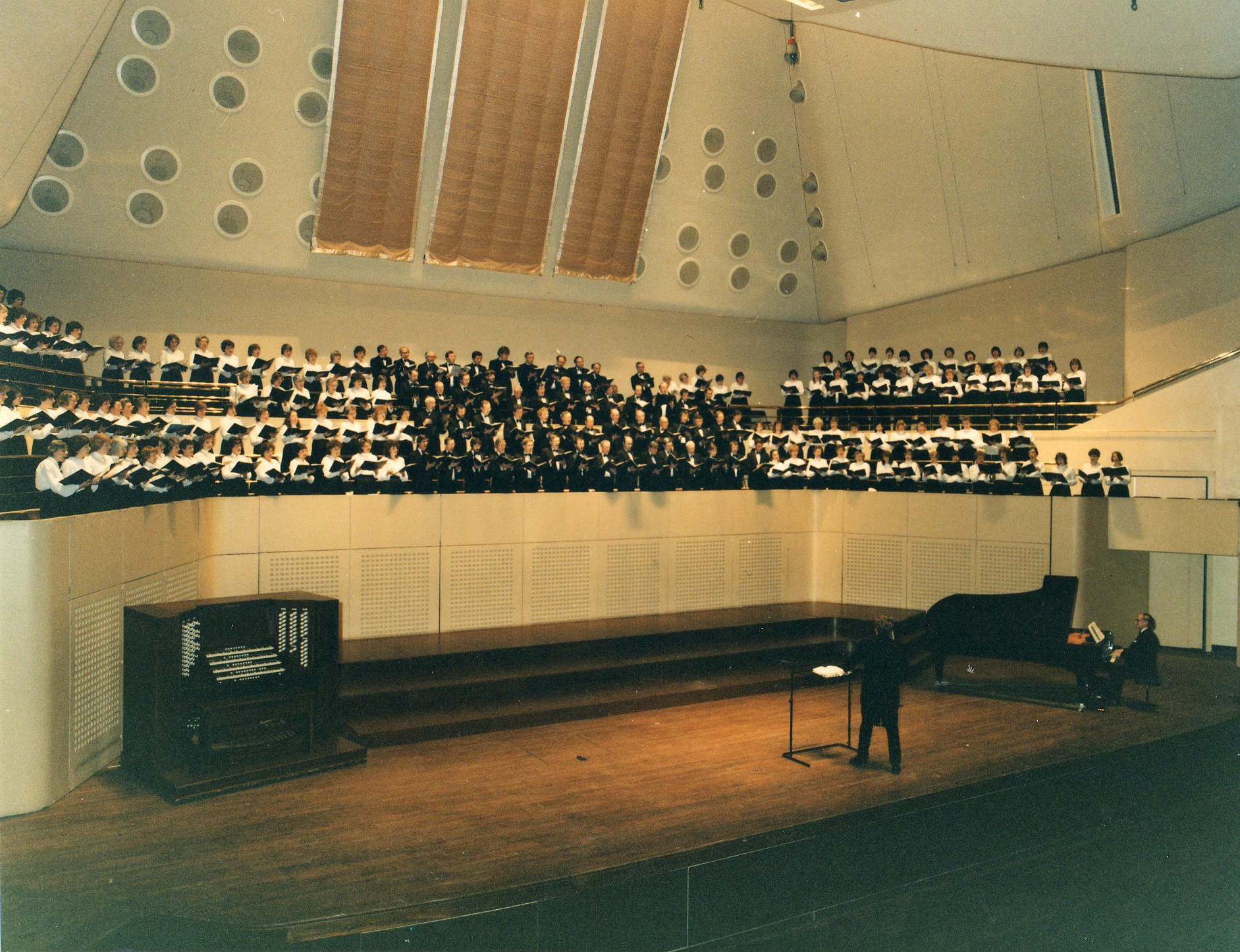 Historical photograph of the choir, conductor and pianist. 
